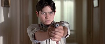 Movie still from “Road to Perdition” (2002), directed by Sam Mendes – A young man holding a gun in his hand; Close Up shot, Low angle