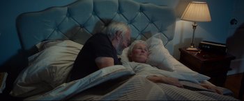 Movie still from “The Wife” (2017), directed by Björn Runge – An older couple laying in a bed together; Medium shot, High angle