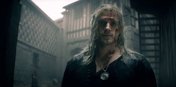 Movie still from “The Witcher” (2019), created by Lauren Schmidt Hissrich – A man with long white hair and a wound on his face; Close Up shot, Over the shoulder angle