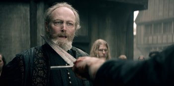 Movie still from “The Witcher” (2019), created by Lauren Schmidt Hissrich – A man with a long beard holding a pair of knifes; Close Up shot, Over the shoulder angle