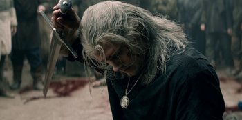 Movie still from “The Witcher” (2019), created by Lauren Schmidt Hissrich – A man with long white hair is holding a sword; Close Up shot, Over the shoulder angle
