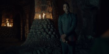 Movie still from “The Witcher” (2019), created by Lauren Schmidt Hissrich – A man standing in front of a pile of human skulls; Medium shot, Low angle