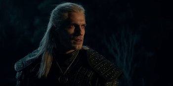 Movie still from “The Witcher” (2019), created by Lauren Schmidt Hissrich – A man with long white hair wearing a black and gold outfit; Close Up shot, Over the shoulder angle