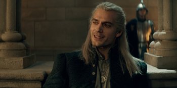 Movie still from “The Witcher” (2019), created by Lauren Schmidt Hissrich – A man with long white hair is smiling for the camera; Close Up shot, Over the shoulder angle