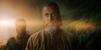 Movie still from “The Witcher” (2019), created by Lauren Schmidt Hissrich – A man with a long beard is looking at the camera; Close Up shot, Low angle