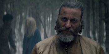 Movie still from “The Witcher” (2019), created by Lauren Schmidt Hissrich – A man with long grey hair and a gray beard; Close Up shot, Low angle