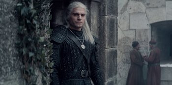 Movie still from “The Witcher” (2019), created by Lauren Schmidt Hissrich – A man with white hair wearing a black outfit; Medium shot, Over the shoulder angle