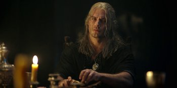 Movie still from “The Witcher” (2019), created by Lauren Schmidt Hissrich – A man with long white hair is sitting at a table; Close Up shot, Low angle