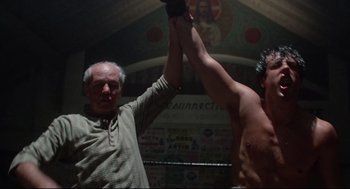 Movie still from “Rocky” (1976), directed by John G. Avildsen – Two men in a boxing ring holding their hands up; Medium shot, Low angle