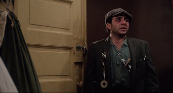 Movie still from “Rocky” (1976), directed by John G. Avildsen – A man wearing a hat standing in front of a door; Medium shot, Low angle