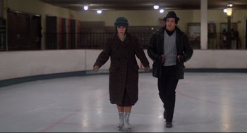 Movie still from “Rocky” (1976), directed by John G. Avildsen – A man and a woman are skating on the rink; Wide shot, Low angle
