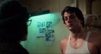 Movie still from “Rocky” (1976), directed by John G. Avildsen – A man standing in front of a mirror in a room; Close Up shot, Over the shoulder angle