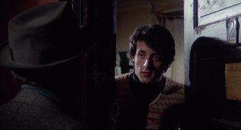 Movie still from “Rocky” (1976), directed by John G. Avildsen – A man in a sweater looking at the camera; Medium shot, Over the shoulder angle