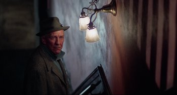Movie still from “Rocky” (1976), directed by John G. Avildsen – An older man wearing a hat standing in front of a lamp; Medium shot, Over the shoulder angle