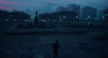 Movie still from “Rocky” (1976), directed by John G. Avildsen – A man standing on a sidewalk in a park at night; Extreme Wide shot, High angle