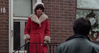 Movie still from “Rocky” (1976), directed by John G. Avildsen – A woman in a red coat and a fur trimmed hat; Medium shot, Over the shoulder angle