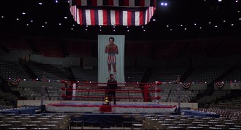 Movie still from “Rocky” (1976), directed by John G. Avildsen – A man standing in a boxing ring in front of an audience; Extreme Wide shot, High angle