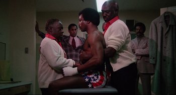 Movie still from “Rocky” (1976), directed by John G. Avildsen – A group of men standing next to each other in a room; Medium shot, Low angle