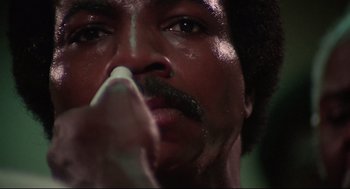 Movie still from “Rocky” (1976), directed by John G. Avildsen – A man's face with a mustache; Extreme Close Up shot, Low angle