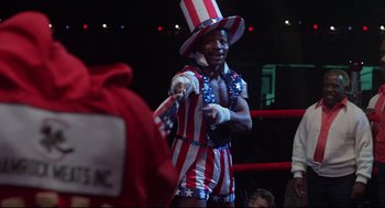 Movie still from “Rocky” (1976), directed by John G. Avildsen – A man wearing a patriotic hat in a boxing ring; Medium shot, Low angle