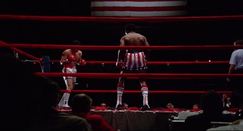 Movie still from “Rocky” (1976), directed by John G. Avildsen – Two boxers in a boxing ring during a match; Wide shot, Low angle