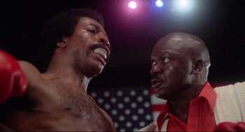 Movie still from “Rocky” (1976), directed by John G. Avildsen – Two men in a boxing ring one of whom is yelling at the other; Close Up shot, Low angle