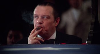 Movie still from “Rocky” (1976), directed by John G. Avildsen – A person wearing a suit smoking a cigarette; Close Up shot, Low angle