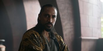 Movie still from “The Witcher” (2019), created by Lauren Schmidt Hissrich – A man with long black hair and a long beard; Close Up shot, Low angle