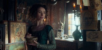 Movie still from “The Witcher” (2019), created by Lauren Schmidt Hissrich – A woman in a green dress holding a bowl; Medium shot, Over the shoulder angle
