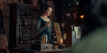 Movie still from “The Witcher” (2019), created by Lauren Schmidt Hissrich – A woman standing next to a table with candles; Medium shot, Over the shoulder angle