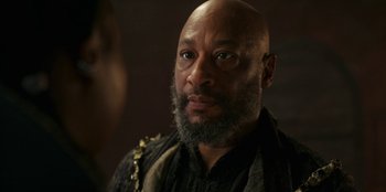 Movie still from “The Witcher” (2019), created by Lauren Schmidt Hissrich – A bald man with a beard and a black shirt; Close Up shot, Over the shoulder angle