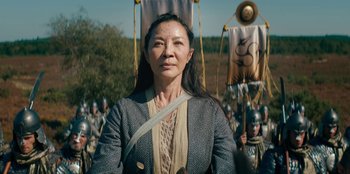 Movie still from “The Witcher” (2019), created by Lauren Schmidt Hissrich – An asian woman standing in front of a group of people; Medium shot, Low angle