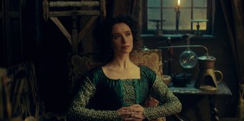 Movie still from “The Witcher” (2019), created by Lauren Schmidt Hissrich – A woman sitting in a chair wearing a green dress; Medium shot, Over the shoulder angle