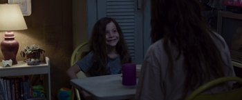 Movie still from “Room” (2015), directed by Lenny Abrahamson – A young girl sitting at a table with a purple cup; Medium shot, Over the shoulder angle