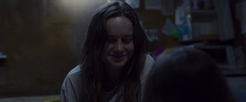 Movie still from “Room” (2015), directed by Lenny Abrahamson – A woman with long dark hair smiling at the camera; Close Up shot, Over the shoulder angle