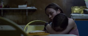 Movie still from “Room” (2015), directed by Lenny Abrahamson – A woman holding a child in her arms at a table; Close Up shot, Over the shoulder angle