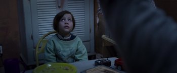 Movie still from “Room” (2015), directed by Lenny Abrahamson – A little girl sitting at a table looking up; Medium shot, Over the shoulder angle