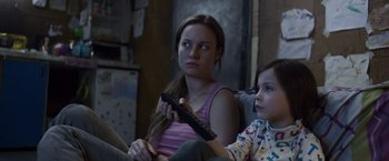 Movie still from “Room” (2015), directed by Lenny Abrahamson – A woman sitting next to a little girl holding a remote control; Close Up shot, Over the shoulder angle