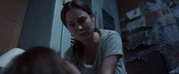 Movie still from “Room” (2015), directed by Lenny Abrahamson – A young woman is sitting in front of a door looking at the camera; Close Up shot, Over the shoulder angle