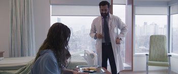 Movie still from “Room” (2015), directed by Lenny Abrahamson – A man in a white lab coat standing in front of a woman; Medium shot, Over the shoulder angle