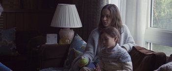 Movie still from “Room” (2015), directed by Lenny Abrahamson – A woman sitting next to a young girl on a couch; Medium shot, Over the shoulder angle