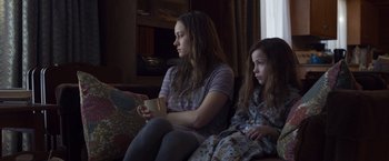 Movie still from “Room” (2015), directed by Lenny Abrahamson – Two young women sitting on a couch watching television; Medium shot, Over the shoulder angle