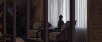 Movie still from “Room” (2015), directed by Lenny Abrahamson – A person sitting in front of a large window; Medium shot, High angle