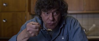 Movie still from “Room” (2015), directed by Lenny Abrahamson – A man holding a piece of food in one hand and a spoon in the other; Close Up shot, Low angle