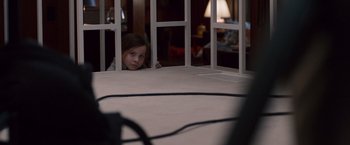 Movie still from “Room” (2015), directed by Lenny Abrahamson – A young girl looking through a window at a table; Medium shot, Over the shoulder angle