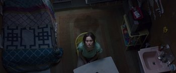 Movie still from “Room” (2015), directed by Lenny Abrahamson – A woman sitting on a chair in a dark room; Medium shot, Overhead angle