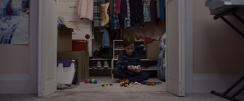Movie still from “Room” (2015), directed by Lenny Abrahamson – A young boy sitting on the floor playing with toys; Wide shot, Overhead angle