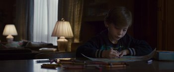 Movie still from “Room” (2015), directed by Lenny Abrahamson – A young boy sitting at a table doing a drawing; Close Up shot, High angle