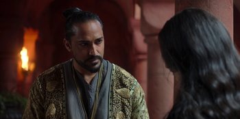 Movie still from “The Witcher” (2019), created by Lauren Schmidt Hissrich – A man with long hair and a beard wearing a robe; Close Up shot, Over the shoulder angle