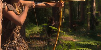Movie still from “The Witcher” (2019), created by Lauren Schmidt Hissrich – A man holding a bow and arrow in the woods; Medium shot, Low angle